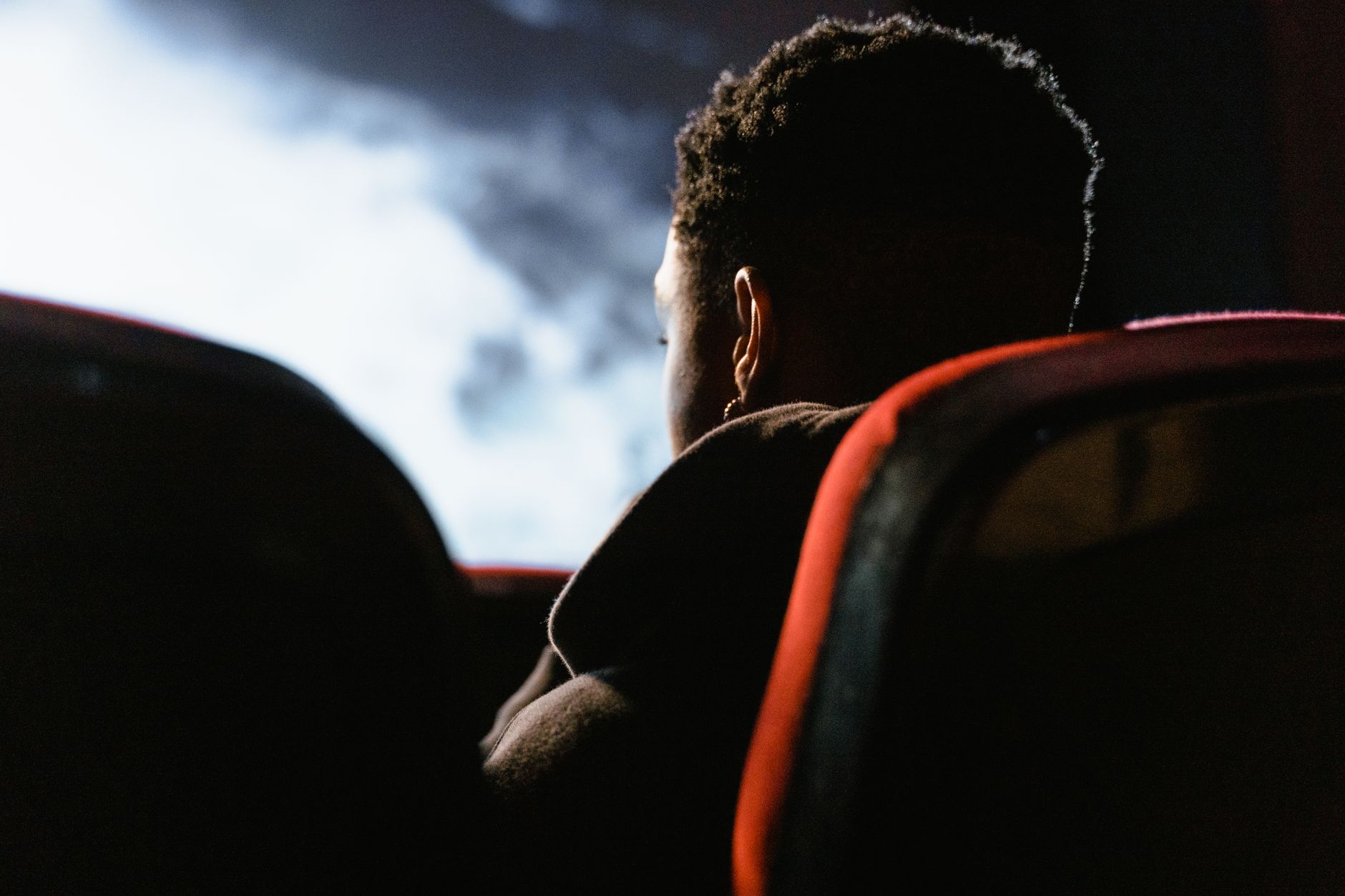 Une personne assise dans un cinéma regarde un film sur grand écran, enveloppée dans une ambiance sombre.